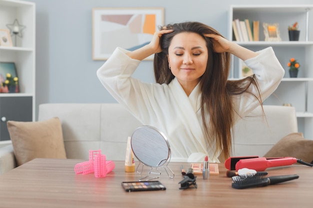 Young asian woman with dark long hair sitting at the dressing table at home making scalp massage relaxing doing morning makeup routine