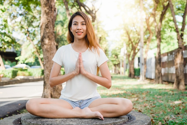 Free photo young asian woman yoga outdoors keep calm and meditates while practicing yoga