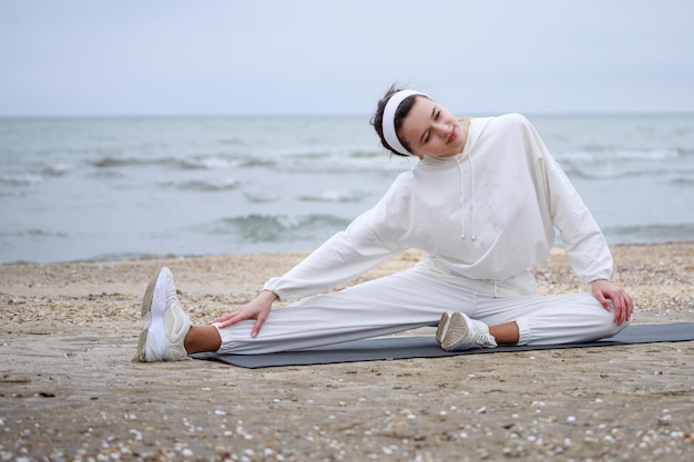 Young athlete at the beach Young girl doing morning exercises High quality photo