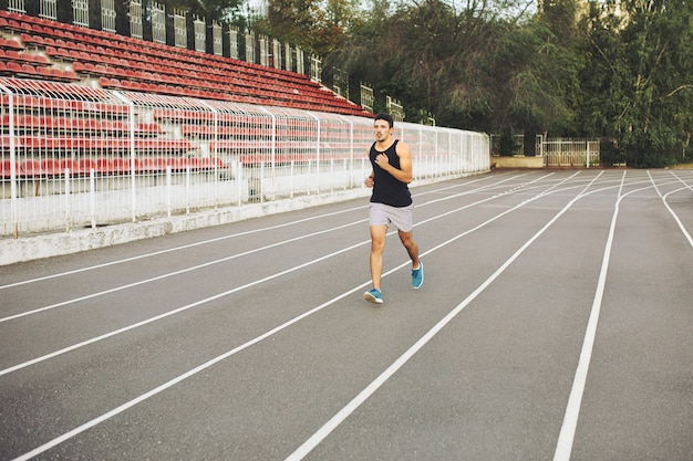 Young athletic man running on the stadium in the morning