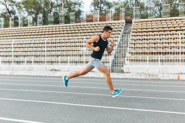 Young athletic man running on the stadium in the morning