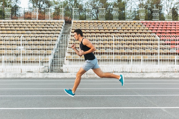 Young athletic man running on the stadium in the morning