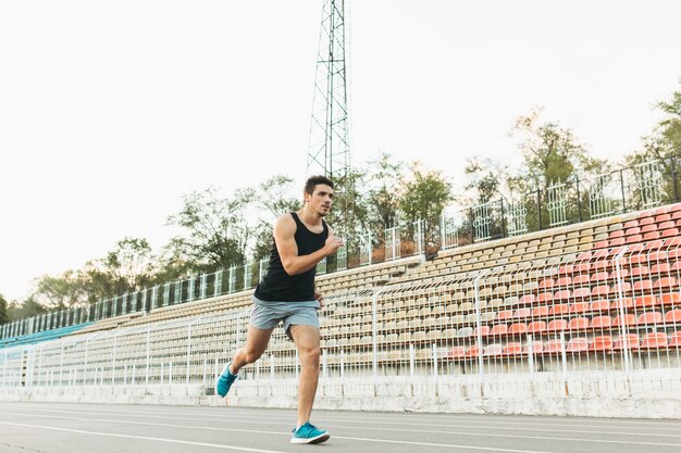 Young athletic man running on the stadium in the morning