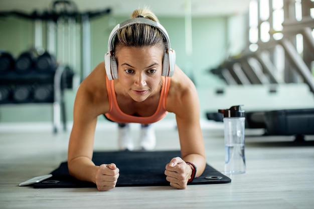 Free Photo young athletic woman in plank pose exercising strength at health club