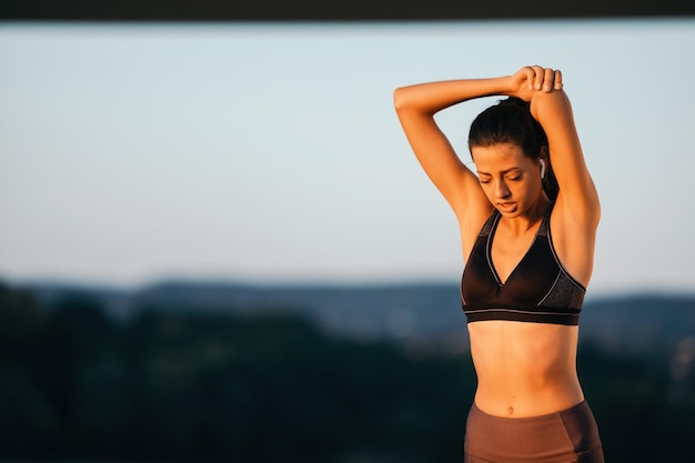 Young athletic woman stretching herself while working out in nature in the morning Copy space