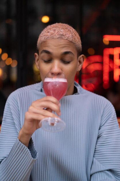 young attractive african american man in cafe with pink cosmopolitan cocktail, fashion shoot. Paris