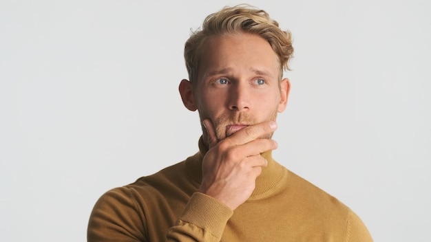 Free photo young attractive blond bearded man keep hand on chin thinking on camera isolated on white background wistful man