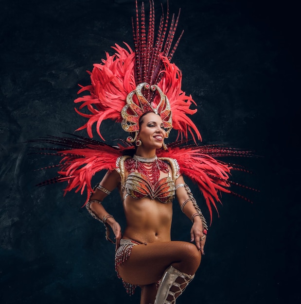 Free Photo young attractive brasil dancer in red feather costume is dancing at small dark studio.