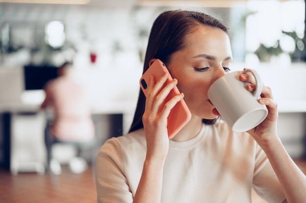 Young attractive businesswoman using her smartphone in office