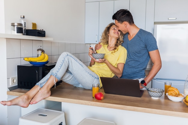 Young attractive couple of man and woman eating breakfast together in morning at kitchen