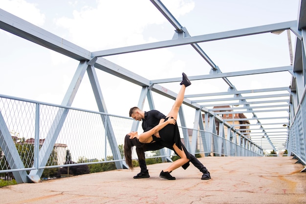 Young attractive couple tangoing on the bridge