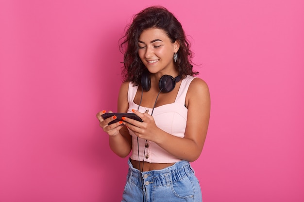 Young attractive curly haired girl standing, having headphones around neck