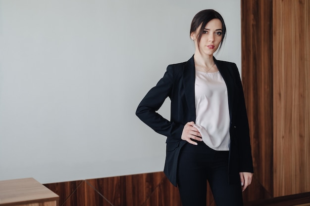 Young attractive emotional girl in business-style clothes in an office or audience