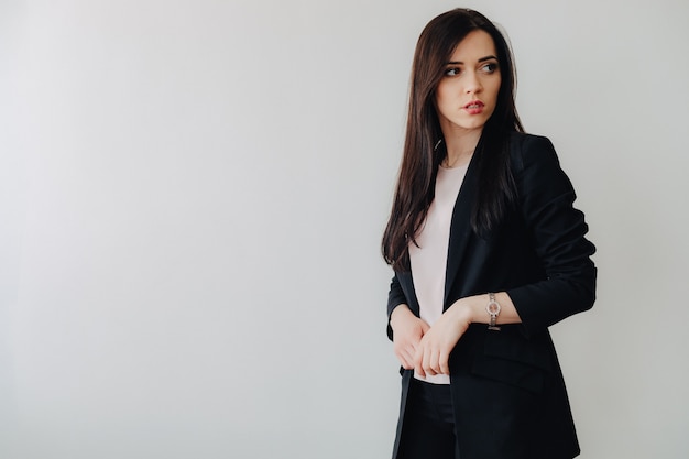 Young attractive emotional girl in business-style clothes on a plain white background in an office or audience