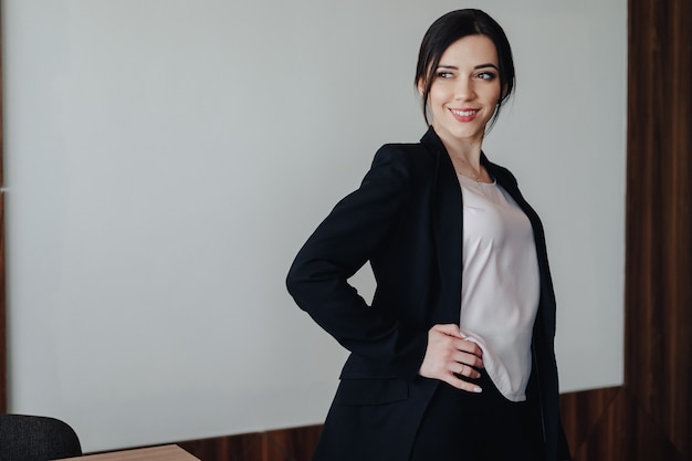 Young attractive emotional girl in business-style clothes on a plain white surface in an office or audience