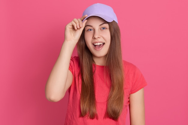 Free photo young attractive excited female wearing casual clothing and baseball cap, looks happy, yelling something, touching cap visor