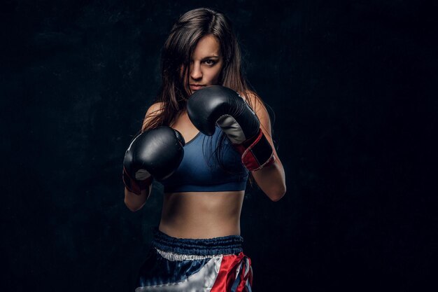 Young attractive female boxer with long hair and boxing gloves is ready to fight.