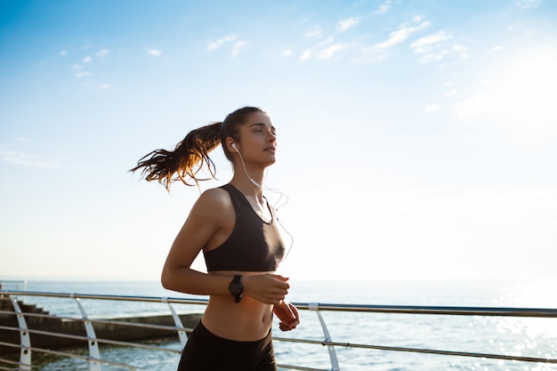 young attractive fitness girl jogging by the sea