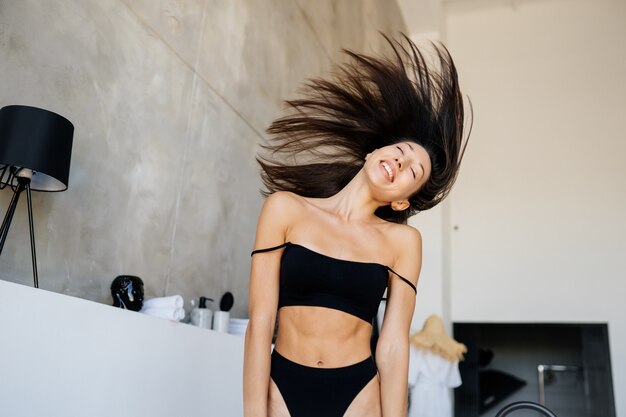 Young attractive girl in black lingerie shaking her head with hair in the bathroom