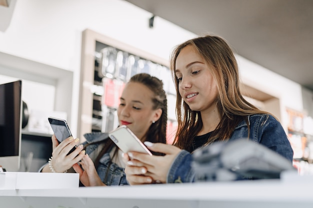 Young attractive girls in electronics store buy new phone