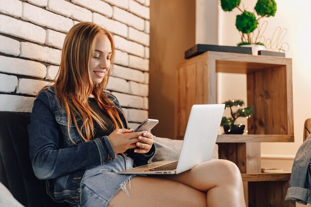 Young attractive girls in electronics store in lounge area on sofa with laptops and phones