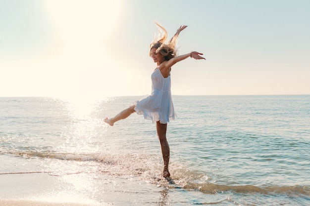 Free photo young attractive happy woman dancing turning around by sea beach sunny summer fashion style