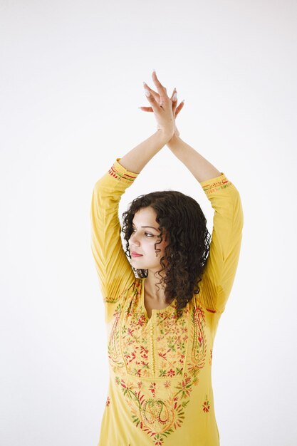 Young attractive Indian woman in traditional dress. Woman dancing against white background.