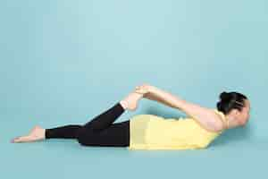 Free photo young attractive lady in yellow shirt and black trousers doing yoga postures