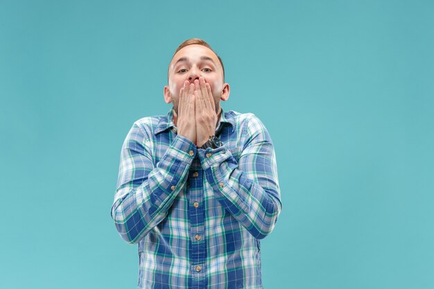 The young attractive man looking suprised isolated on blue