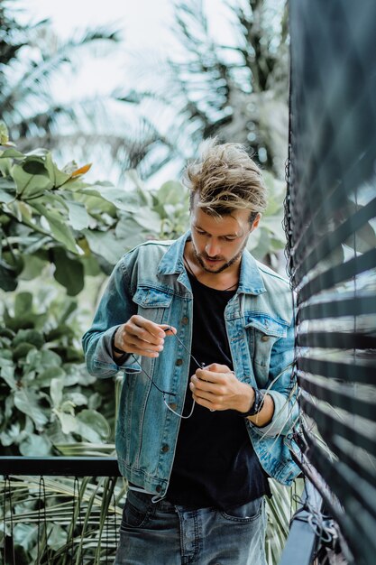 young attractive man posing in a tropical location, on a background of palm trees and greenery