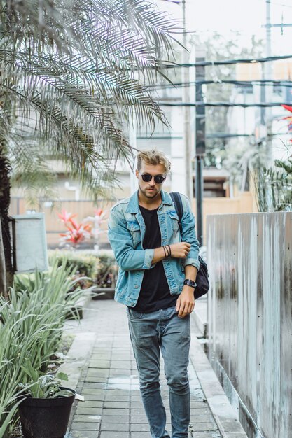 young attractive man posing in a tropical location, on a background of palm trees and greenery