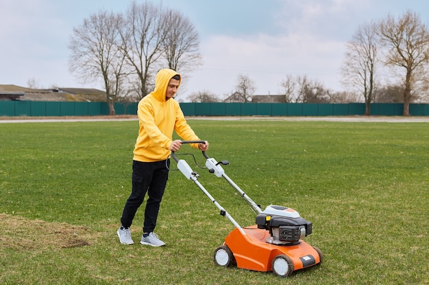 Free photo young attractive man trimming grass with cutter