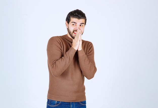 young attractive model in brown sweater posing on white wall.