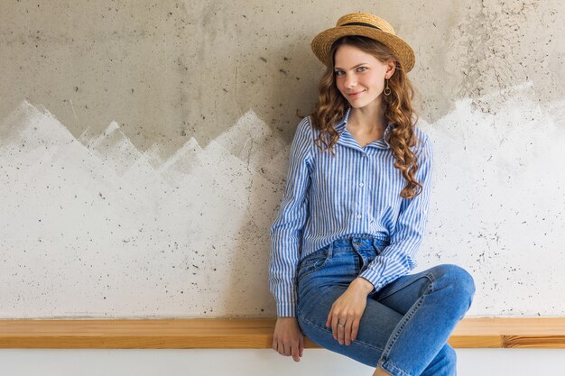 Young attractive stylish woman sitting at wall