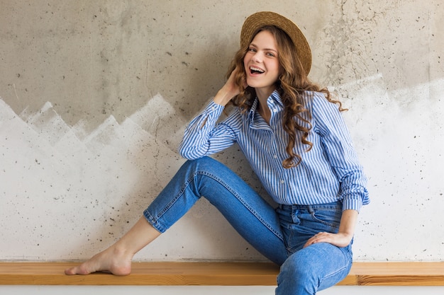 Free photo young attractive stylish woman sitting at wall