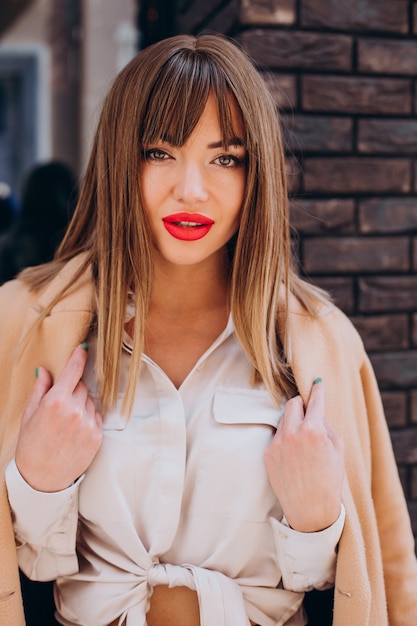 Free photo young attractive woman in beige coat posing in the street