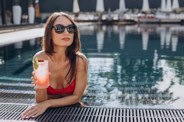 Free photo young attractive woman by the pool drinking cocktail