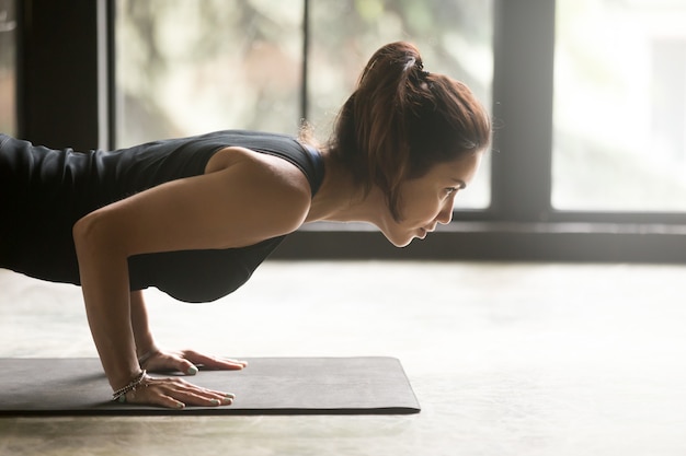 Young attractive woman in chaturanga dandasana pose