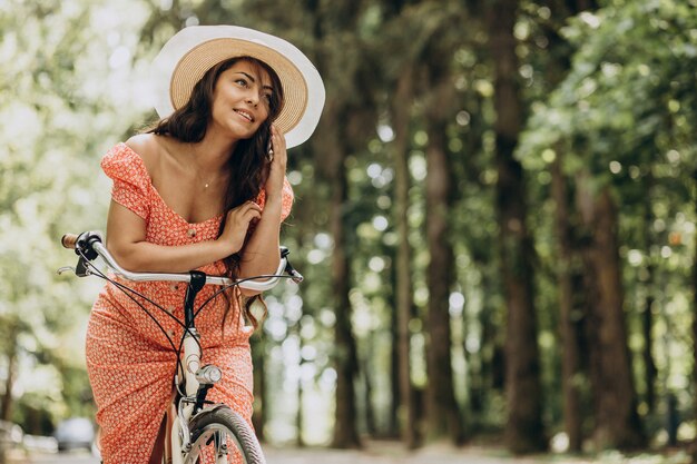 Young attractive woman in dress riding bicycle and using phone