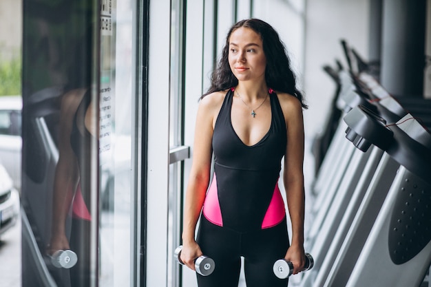 Young attractive woman at the gym with dumbbells