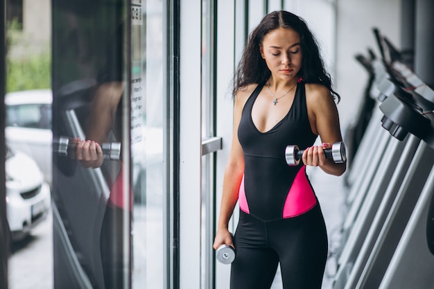 Young attractive woman at the gym with dumbbells