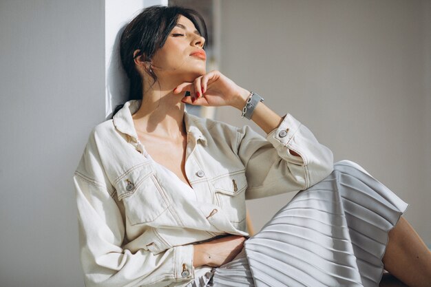 Young attractive woman model sitting by the wall