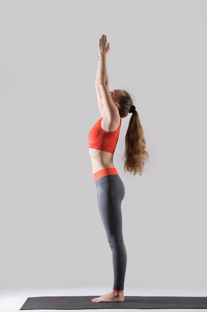 Free photo young attractive woman standing in tadasana pose, grey studio ba