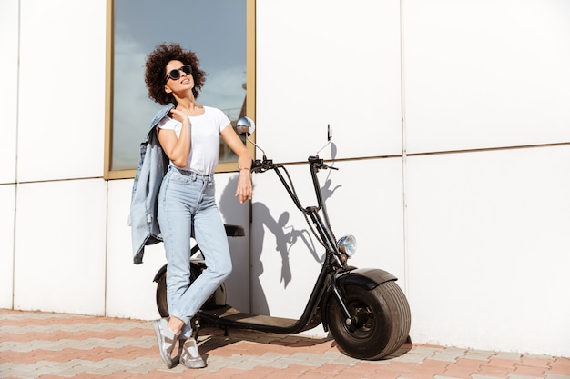 Young attractive woman in sunglasses posing while standing