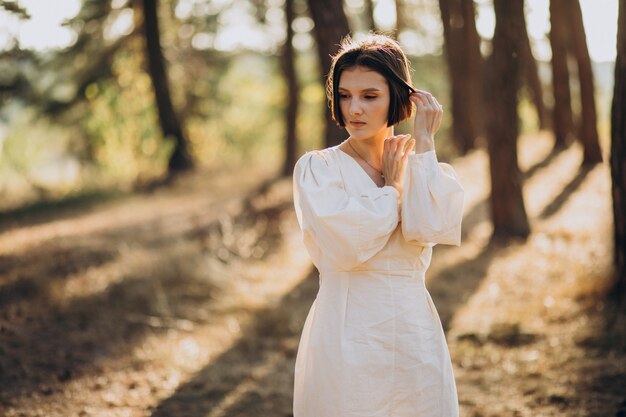 Free Photo young attractive woman in white dress in forest