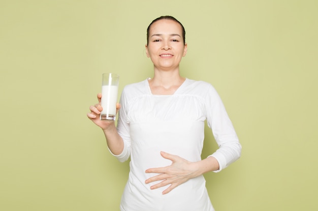 Free Photo young attractive woman in white shirt smiling and holding glass with milk