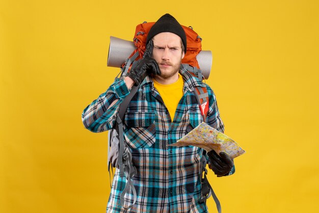 young backpacker with black hat holding map thinking about something