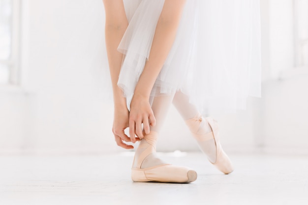 Young ballerina dancing, closeup on legs and shoes, standing in pointe position.