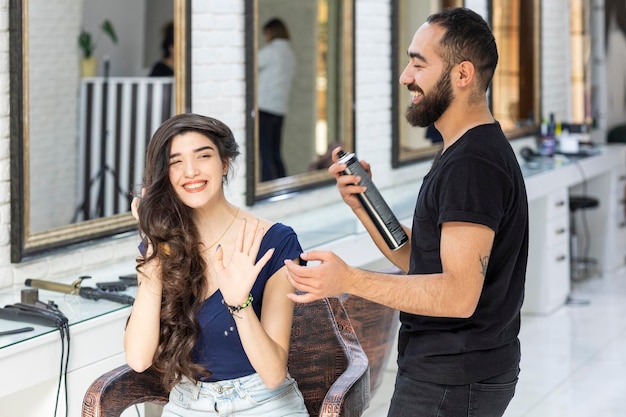 Free photo young barber holding spray and his client laughing with him