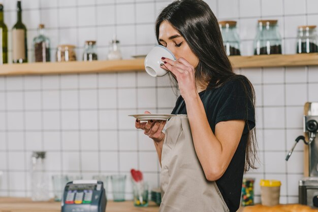 Young barista drinking hot beverage